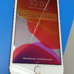 Smartfon iPhone z włączonym ekranem blokady, leżący na niebieskiej macie serwisowej, wyświetlający godzinę 10:51 i komunikat o konieczności dokończenia konfiguracji.