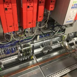 Panel sterowania z czerwonymi modułami SEW Movitrac, licznymi przewodami w różnych kolorach i miedzianymi szynami uziemiającymi, widok z góry.