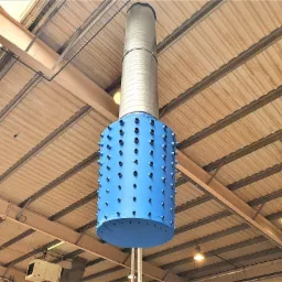 Niebieski cylindryczny element z otworami, część systemu wentylacji przemysłowej, zawieszony pod sufitem hali z widoczną instalacją i oświetleniem.