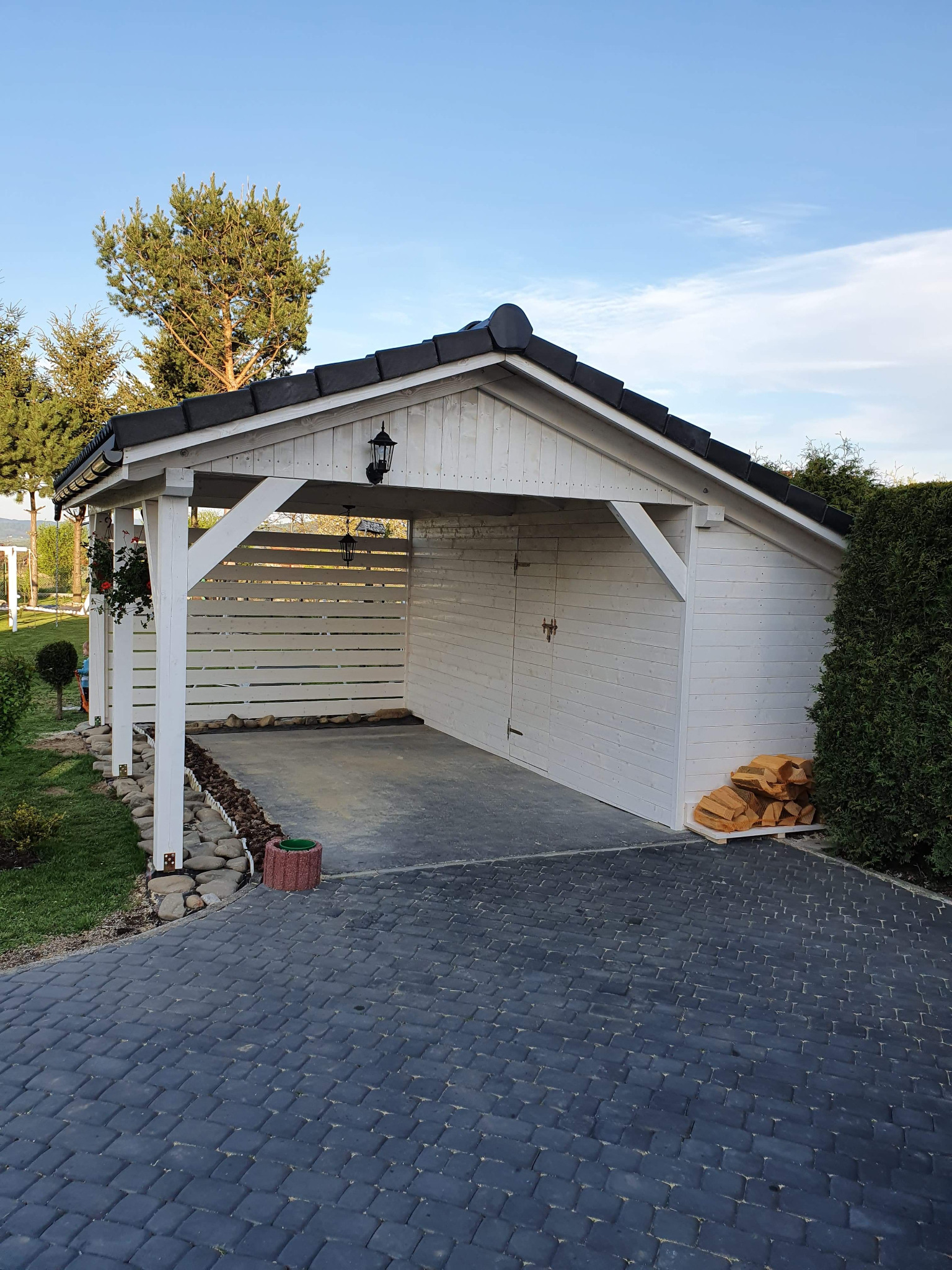 Wiata samochodowa z pomieszczeniem gospodarczym z boku.