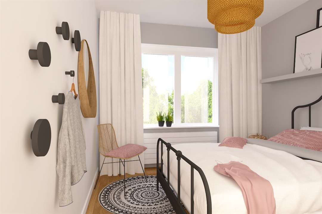 Wnętrze sypialni w stonowanych barwach z łóżkiem z metalową ramą, okrągłym dywanem w geometryczne wzory, rattanowym krzesłem i minimalistycznymi wieszakami na ścianie, na jednym z nich wisi jasny...