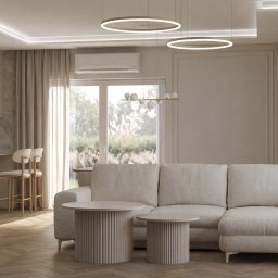 MP ARCHITEKTURA WNĘTRZ PAULINA TRACZ - Jasne wnętrze salonu z parkietem w jodełkę, beżową sofą narożną, okrągłymi stolikami kawowymi i minimalistycznym kominkiem. Widok na kuchnię i okno z widokiem na zieleń.