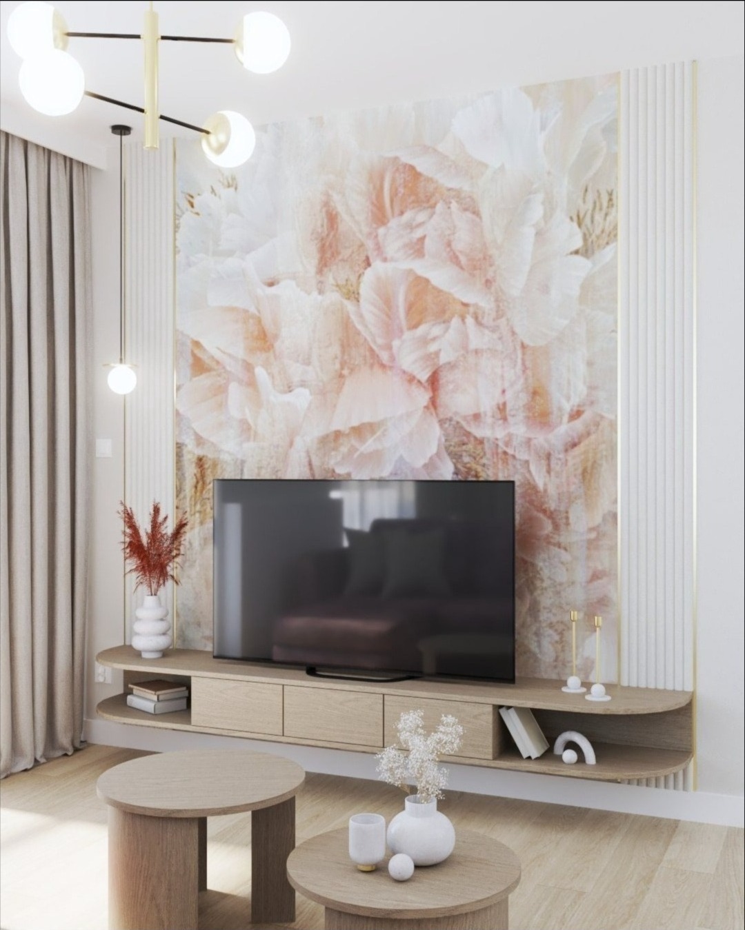 Jasny salon z telewizorem na szafce RTV, nad którym wisi tapeta w kwiaty. Na pierwszym planie dwa okrągłe stoliki kawowe z dekoracjami.