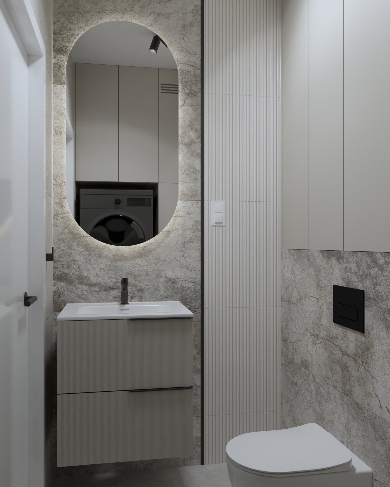 Nowoczesna łazienka w odcieniach szarości z umywalką z szafką z ryflowanym frontem, podświetlanym owalnym lustrem, toaletą i pralką widoczną w odbiciu lustra.