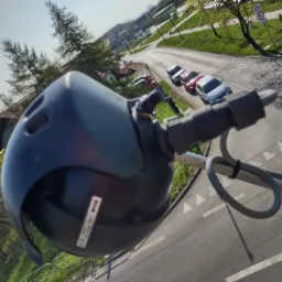 Kamera przemysłowa zamontowana na słupie, widok z góry na ulicę z samochodami i zielenią w tle.