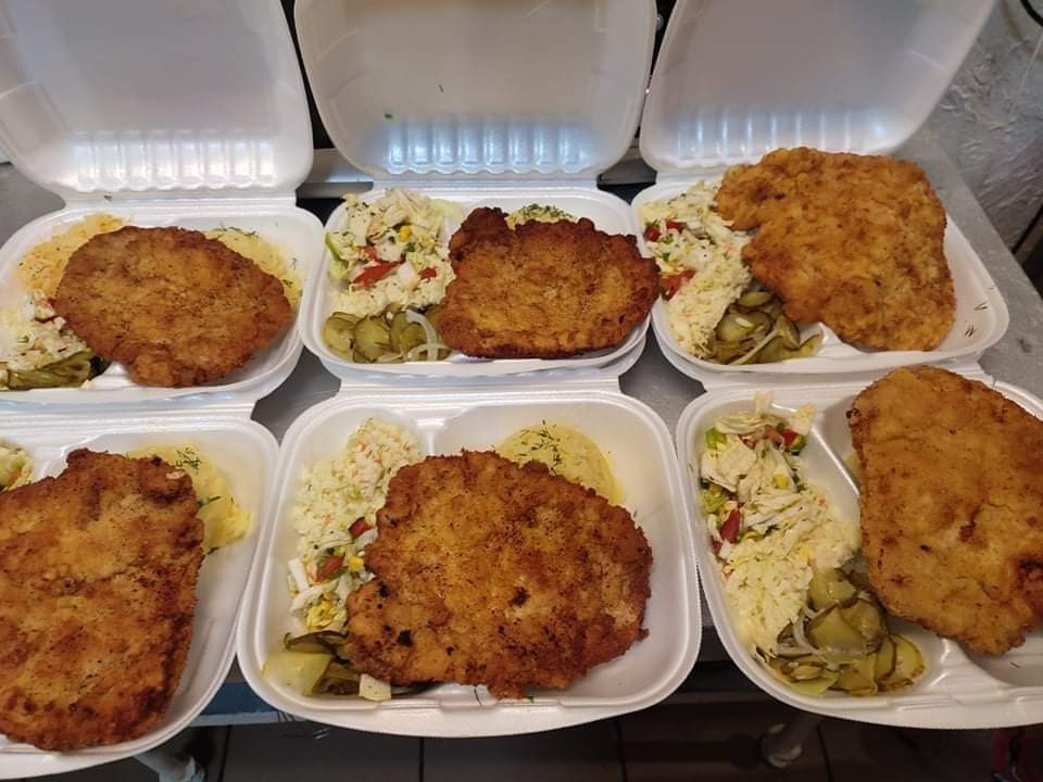Sześć porcji obiadowych w białych, styropianowych pudełkach: kotlet schabowy, ziemniaki z koperkiem i surówka z ogórkami konserwowymi.