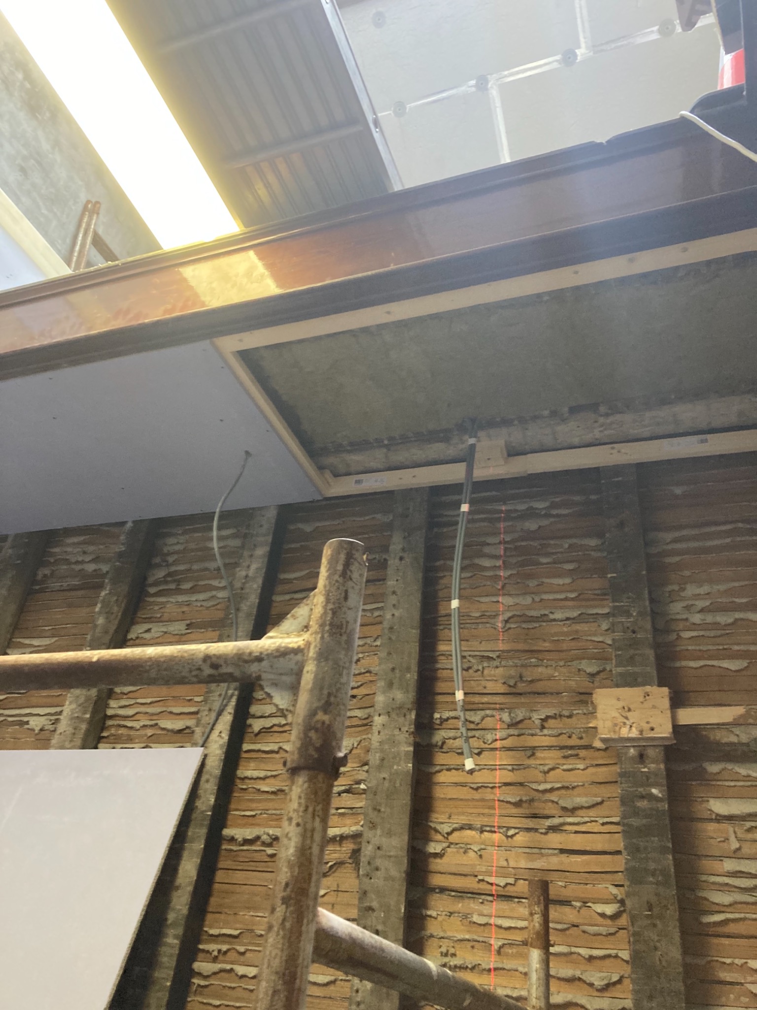 Drewniana ściana z widocznym fragmentem konstrukcji poddasza i schodami rusztowania, ukazująca etap przygotowania do prac wykończeniowych.