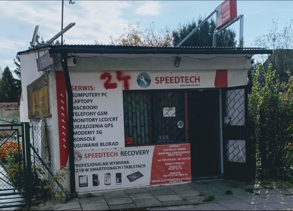 Fasada małego punktu serwisowego Speedtech z ofertą naprawy komputerów, laptopów, telefonów, monitorów i innych urządzeń, z widocznym napisem 'Recovery' sugerującym specjalizację w odzyskiwaniu...