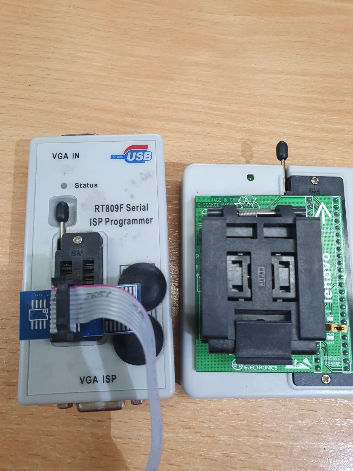 Dwa programatory RT809F Serial ISP na drewnianym blacie, jeden z podłączonym kablem, drugi z widocznym gniazdem IC-SOCKET MADE IN CHINA.