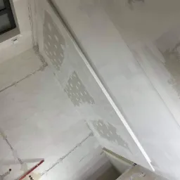 Montaż płyty karton gips na suficie z widocznymi punktami mocowania i instalacją elektryczną w trakcie prac wykończeniowych.