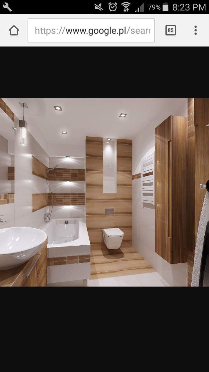 Nowoczesna łazienka z brązowo-białymi płytkami, wolnostojącą umywalką, podwieszaną toaletą i drewnianą szafką, oświetlona punktowymi lampami sufitowymi.