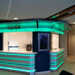 Nowoczesny kiosk z napojami 'SLUSH' z podświetleniem LED w kolorze turkusowym, wkomponowany w jasne wnętrze z elementami drewnianymi na suficie.