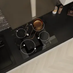 Czarny blat kuchenny z marmurowym wzorem, płyta indukcyjna z miedzianym rondlem, czarny zlew i drewniana podłoga ułożona w jodełkę, widok z góry.