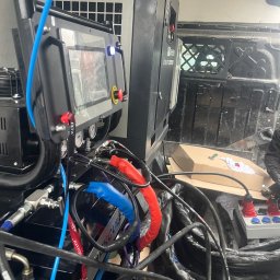 P.H.U.AKRO Marek Zalewski - Sprzęt do natrysku pianki PUR wewnątrz furgonetki: sterownik z ekranem, kompresor, przewody hydrauliczne i zasilające. Widoczne narzędzia i akcesoria.