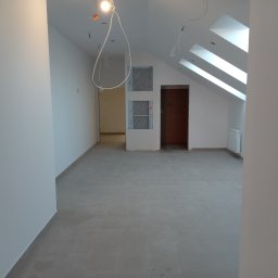 Remonty i Wykończenia Adam Światłoń - Poddasze po remoncie z oknami dachowymi, szarą podłogą z płytek, białymi ścianami i instalacją elektryczną do wykończenia.
