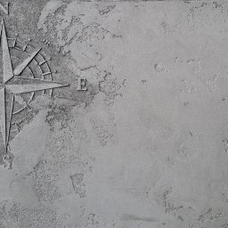 IVAD - Szara ściana z dekoracyjną fakturą i wkomponowaną rozetą kompasową z literami N i E oznaczającymi kierunki.