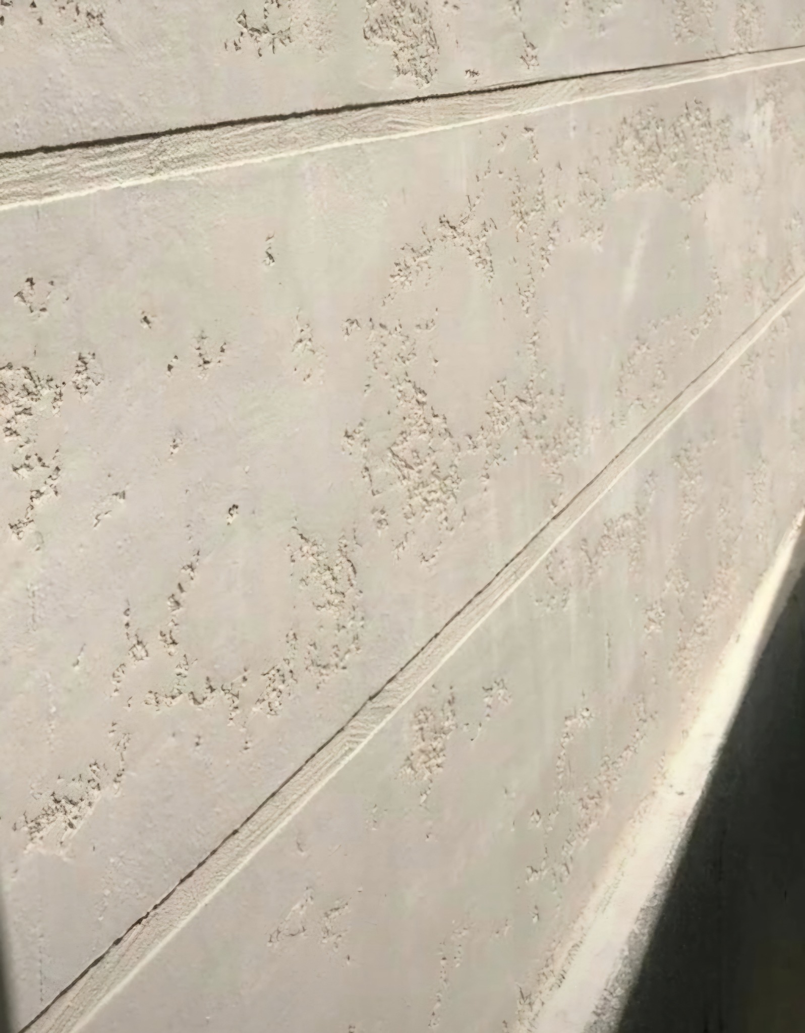 Fragment elewacji z fakturą baranka, z widocznymi poziomymi liniami podziału, oświetlony z boku