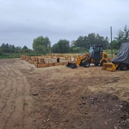 ARDSWELD Arkadiusz Dopierała - Przygotowany teren pod fundamenty z drewnianym szalunkiem i żółtą mini ładowarką na ziemnym placu budowy w pochmurny dzień.