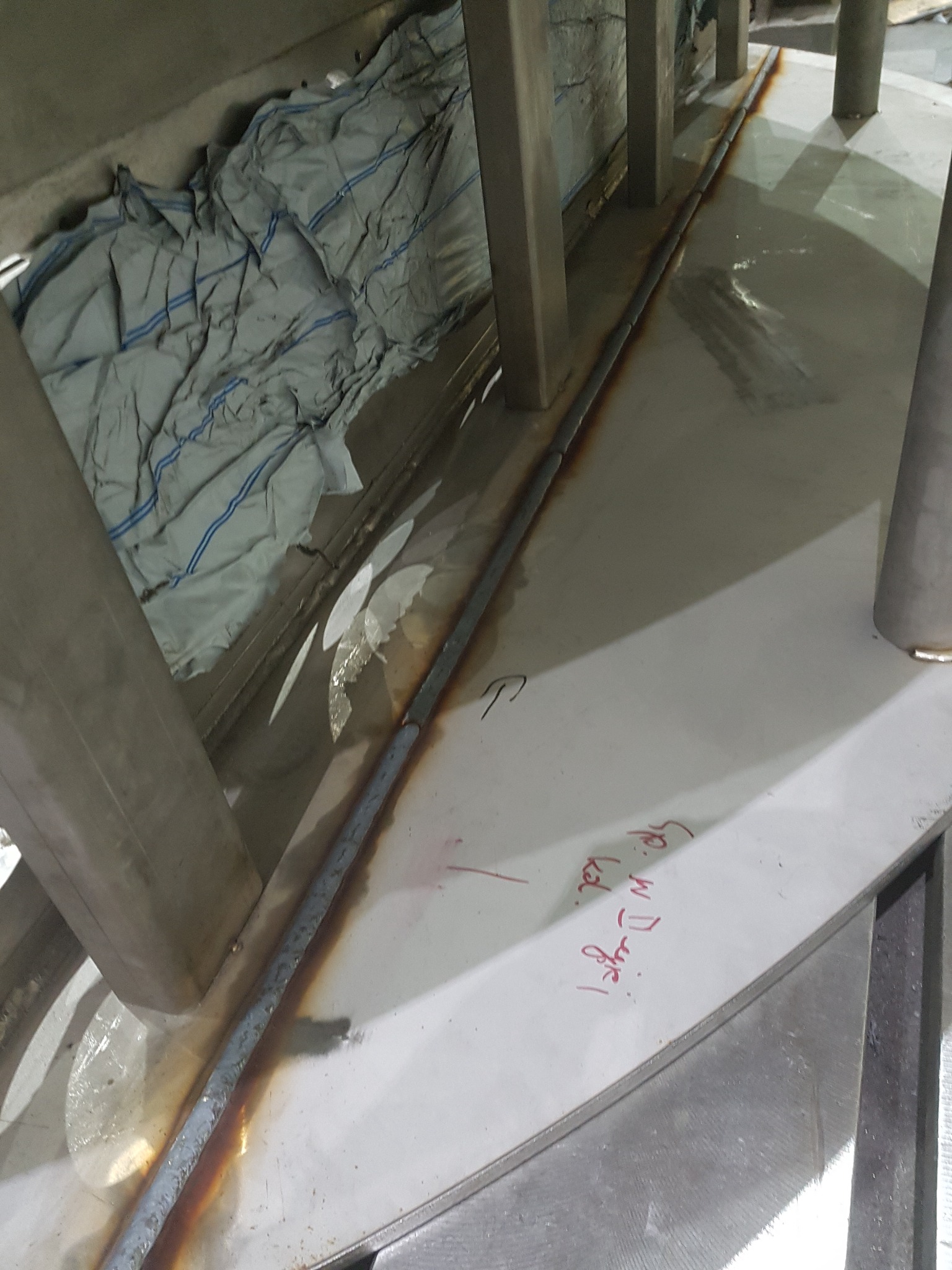 Spoina spawalnicza łącząca elementy konstrukcji stalowej, widoczne ślady po spawaniu i odręczny napis na powierzchni metalu.