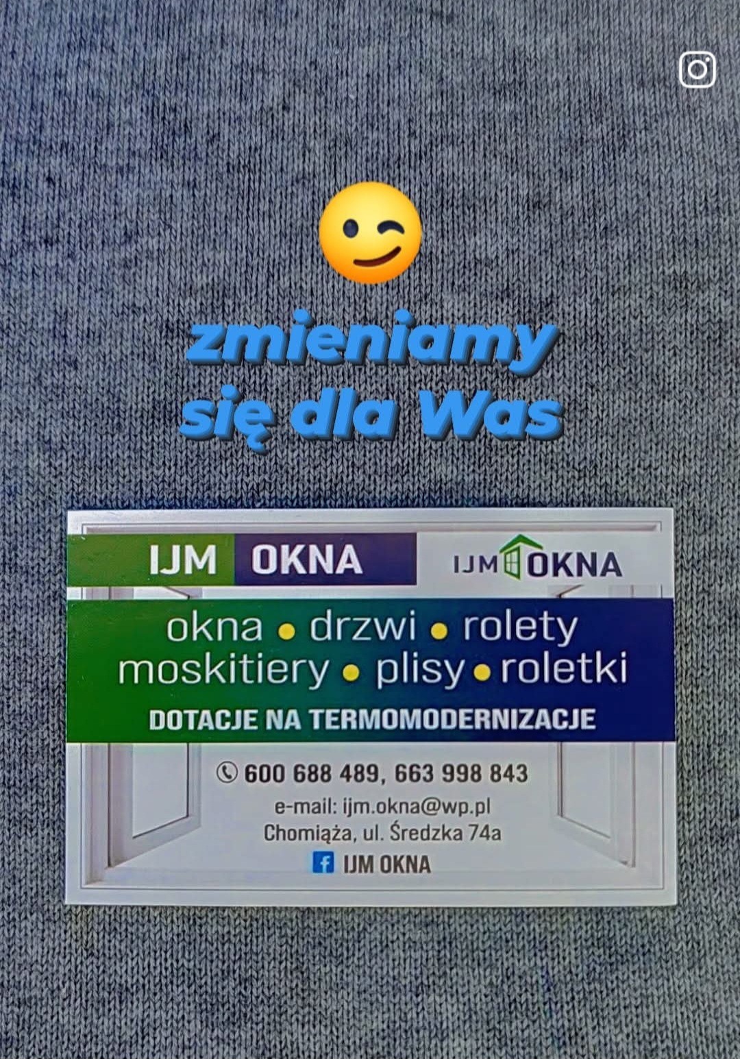 Wizytówka firmy IJM OKNA z ofertą okien, drzwi, rolet i moskitier, umieszczona na szarym tekstylnym tle, z napisem 'zmieniamy się dla Was' i emotikonem mrugającej buźki.