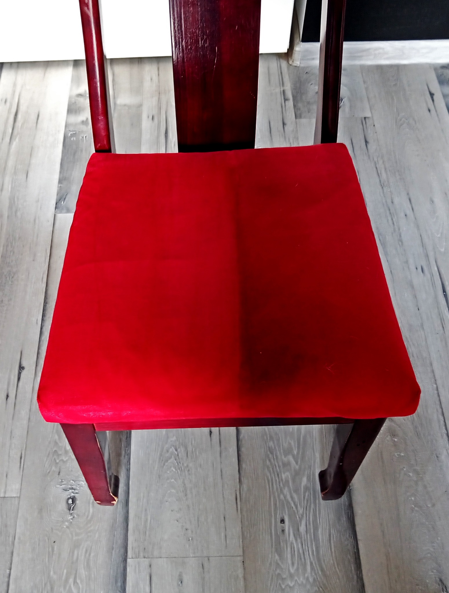 Czerwone welurowe siedzisko krzesła z ciemnego drewna, widoczna różnica w czystości między lewą a prawą stroną siedziska po praniu.