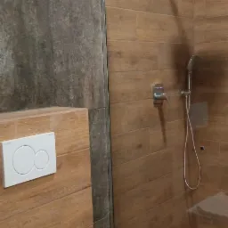 Nowoczesna łazienka w Kaliszu z drewnopodobnymi płytkami, kabiną prysznicową typu walk-in i podtynkową spłuczką WC.