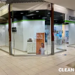 Wnętrze galerii handlowej z widokiem na przeszklony lokal z szyldem 'eSmoking World', czyste podłogi i witryny, widoczny plakat reklamowy wewnątrz lokalu.