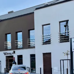 Budynek Winnicy z widocznymi czystymi oknami i elewacją, tablica informacyjna z napisem Winnica Parking, nowoczesna architektura.