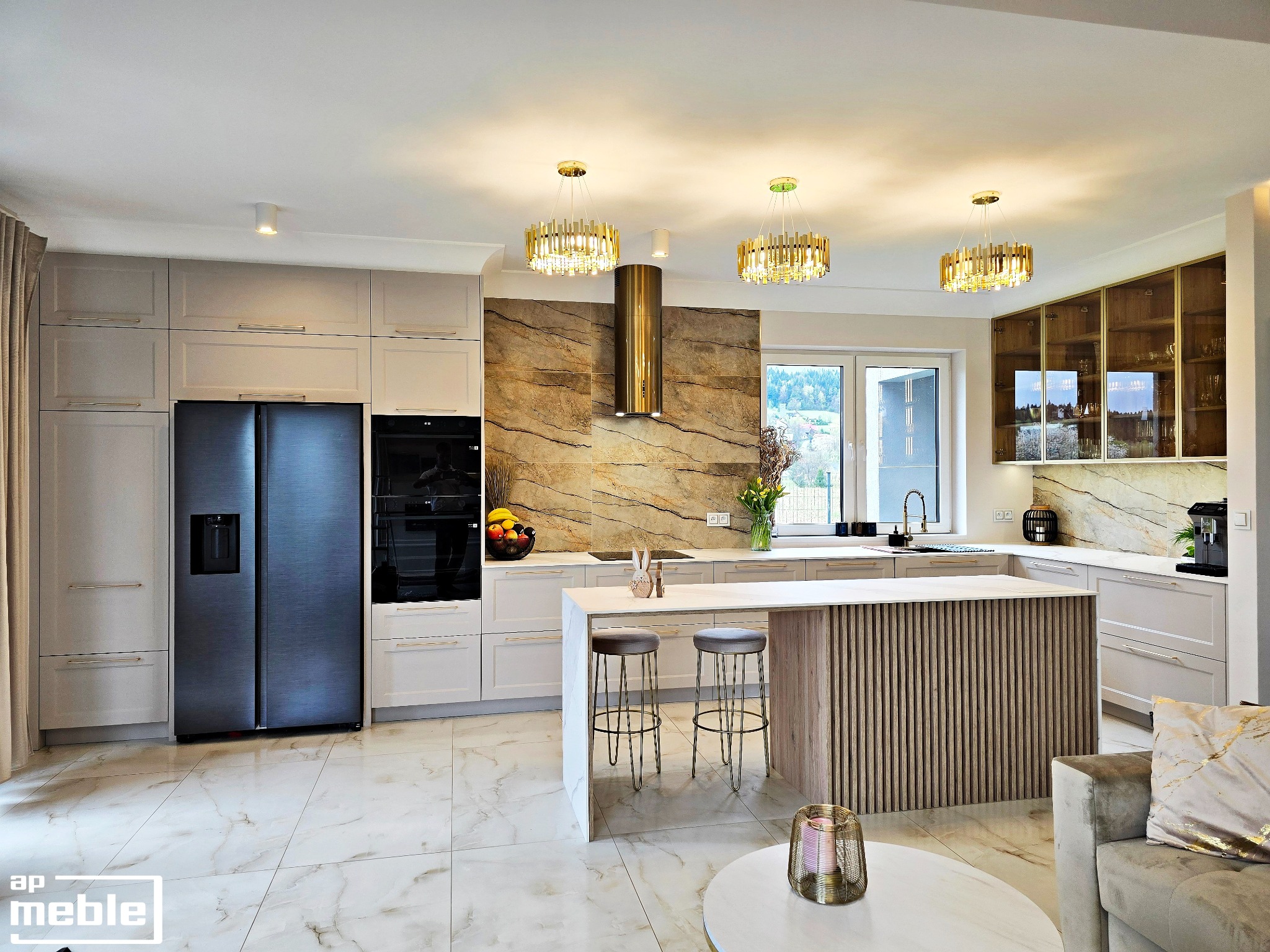 Elegancka kuchnia z wyspą i marmurowym blatem, oświetlona złotymi lampami. Widoczny nowoczesny sprzęt AGD i krzesła barowe, tworzące spójną, luksusową przestrzeń.