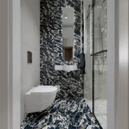 Nowoczesna łazienka z marmurowymi płytkami w odcieniach granatu i bieli, kabina prysznicowa ze szklanymi drzwiami, podwieszana toaleta i umywalka z lustrem z podświetleniem LED.
