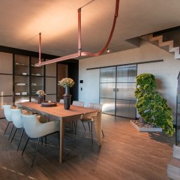 Biuro Projektowe Home Design Ilona Schmidt - Nowoczesna jadalnia z drewnianym stołem, krzesłami w odcieniach beżu, przeszklonymi drzwiami przesuwnymi i schodami z drewnianymi stopniami.