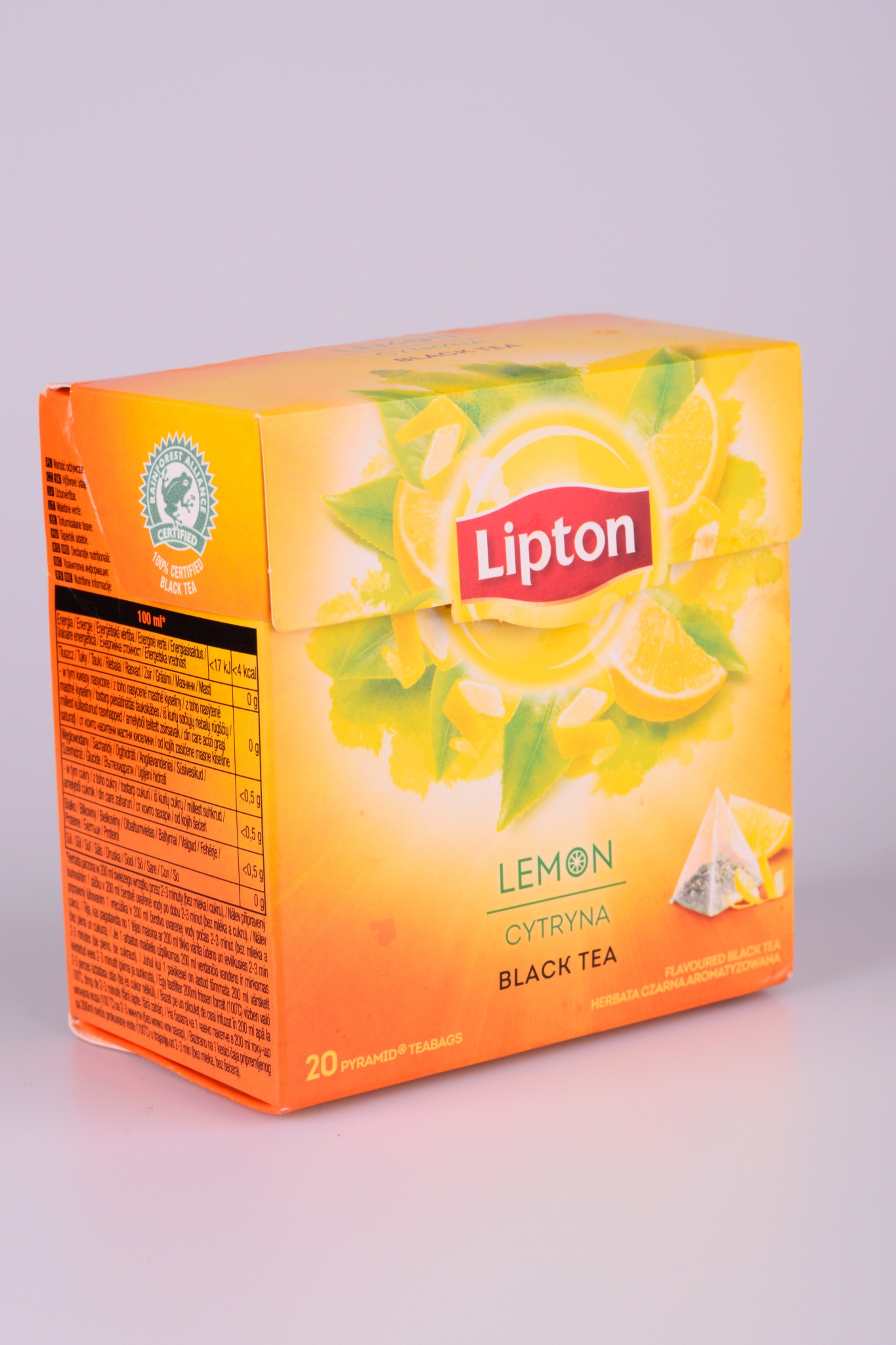 Pudełko herbaty Lipton Lemon Black Tea z wyraźnym logo, plasterkami cytryny i informacjami o certyfikacji Rainforest Alliance.
