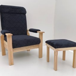 Najmart Sp. z o.o. - Tapicerowany fotel z podnóżkiem na drewnianej ramie, obity czarnym materiałem w romby, na białym tle. Widok z przodu, jasne drewno, minimalistyczny design.