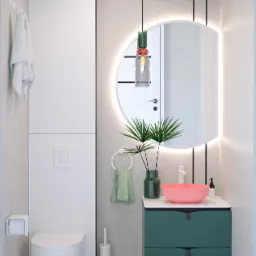 Nowoczesna łazienka z okrągłym lustrem podświetlanym LED, różową umywalką nablatową, zieloną szafką pod umywalką, wiszącą toaletą i drewnianą podłogą ułożoną we wzór jodełki.