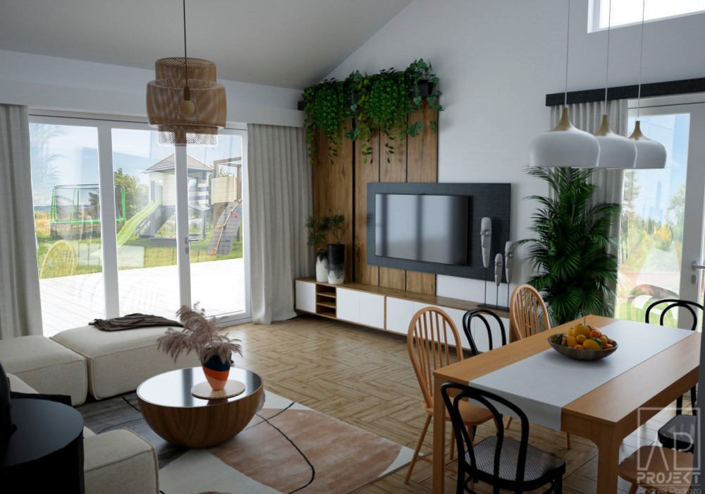 Jasne, przestronne wnętrze salonu z widokiem na plac zabaw przez duże okna, drewniany stół z owocami i designerska lampa wisząca.