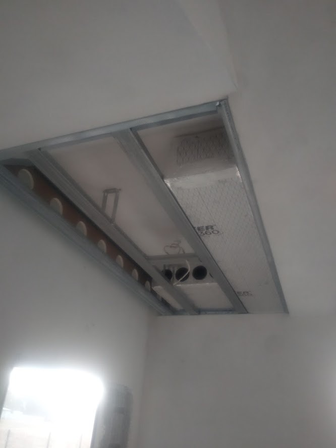 Montaż kanałów wentylacyjnych w suficie podwieszanym, widoczne rury i metalowa konstrukcja stelaża.