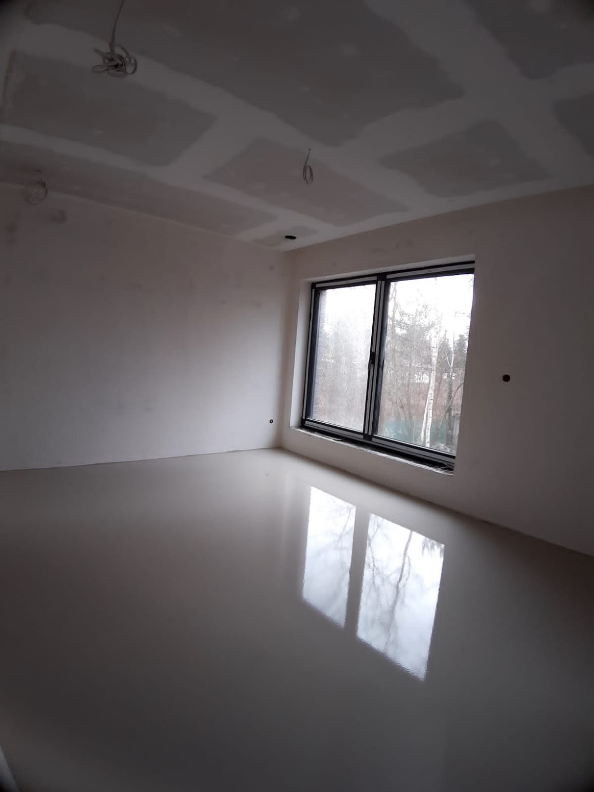 Pokój po wylewce samopoziomującej, widoczne szpachlowane płyty gipsowo-kartonowe na suficie i wystające kable.