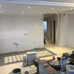 Układanie płytek podłogowych z wzorem w Gdańsku, widoczne narzędzia i materiały budowlane, częściowo ułożona posadzka i przygotowana powierzchnia ścian.