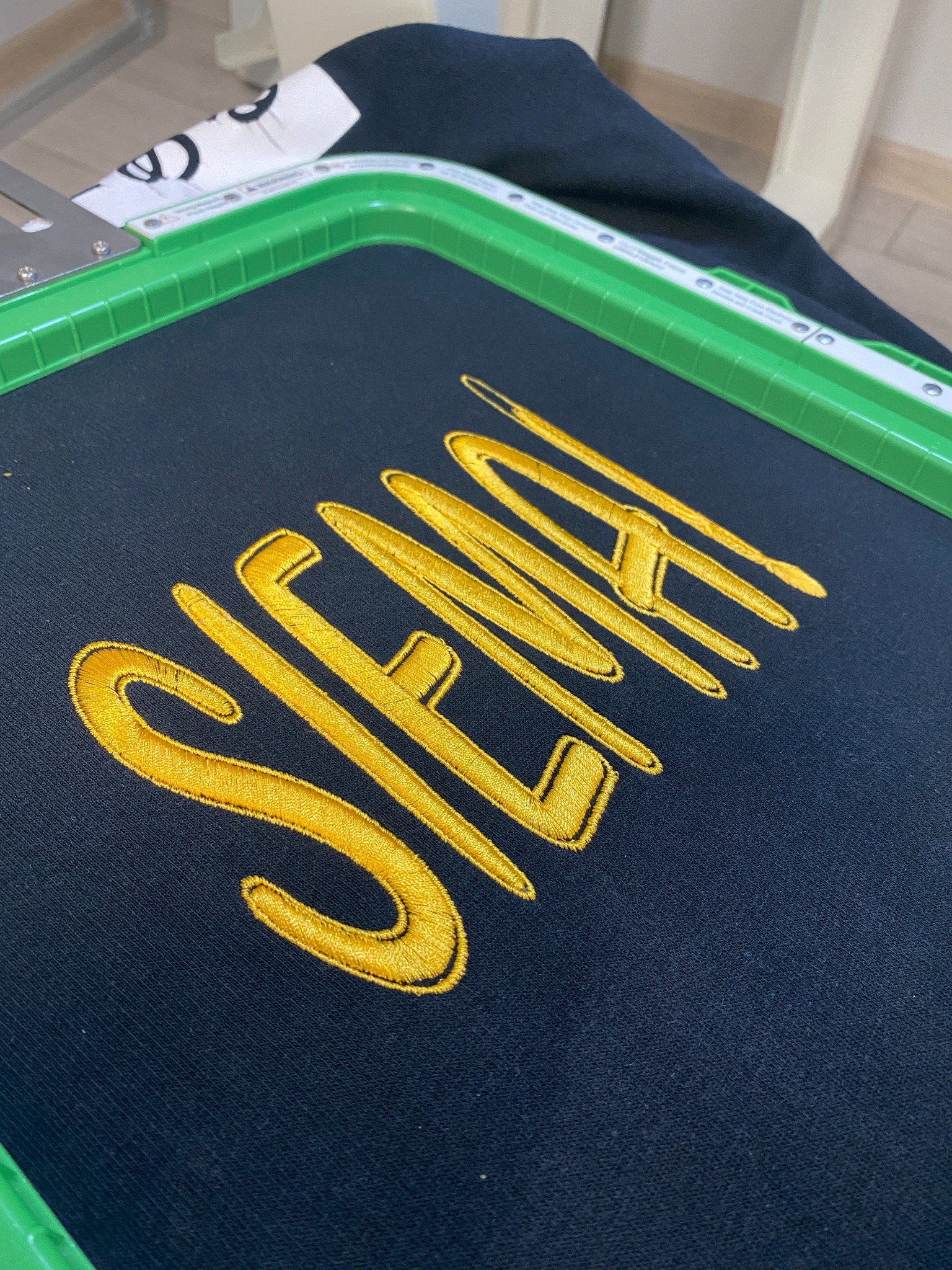 Czarna bluza z wyhaftowanym złotą nicią napisem 'SIENA' w ramce hafciarskiej, wykonana w Targowisku.