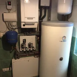 Wnętrze kotłowni z piecem gazowym De Dietrich, zasobnikiem Biawar, oraz elementami instalacji Vaillant, na tle zielonej, ceramicznej ściany i podłogi.