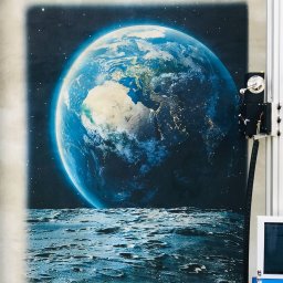 Wilando Sp z o. o. - Automatyczny ploter pionowy drukuje obraz Ziemi widzianej z Księżyca na ścianie.