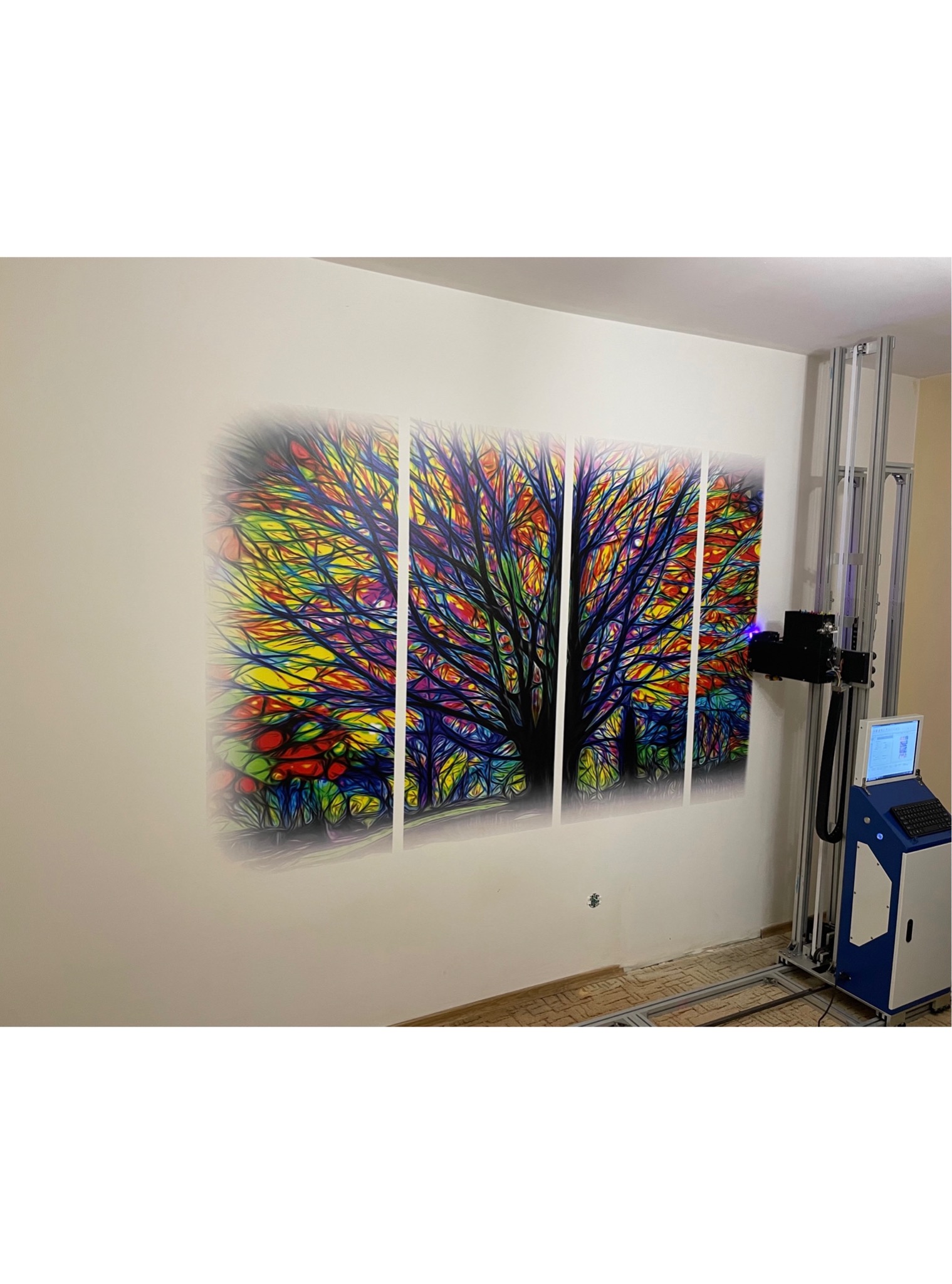 Wielkoformatowy, kolorowy obraz drzewa nanoszony na ścianę za pomocą specjalistycznej drukarki pionowej, z widocznym komputerem sterującym i elementami konstrukcyjnymi urządzenia.
