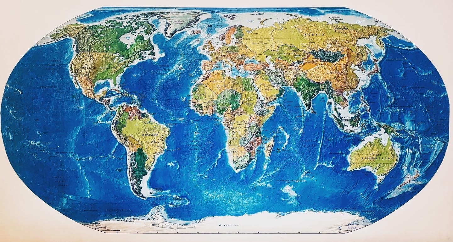 Ilustracja mapy świata w rzucie Mollweide, z wyraźnie zaznaczonymi kontynentami i granicami państw, prezentująca ukształtowanie terenu i głębię oceanów.