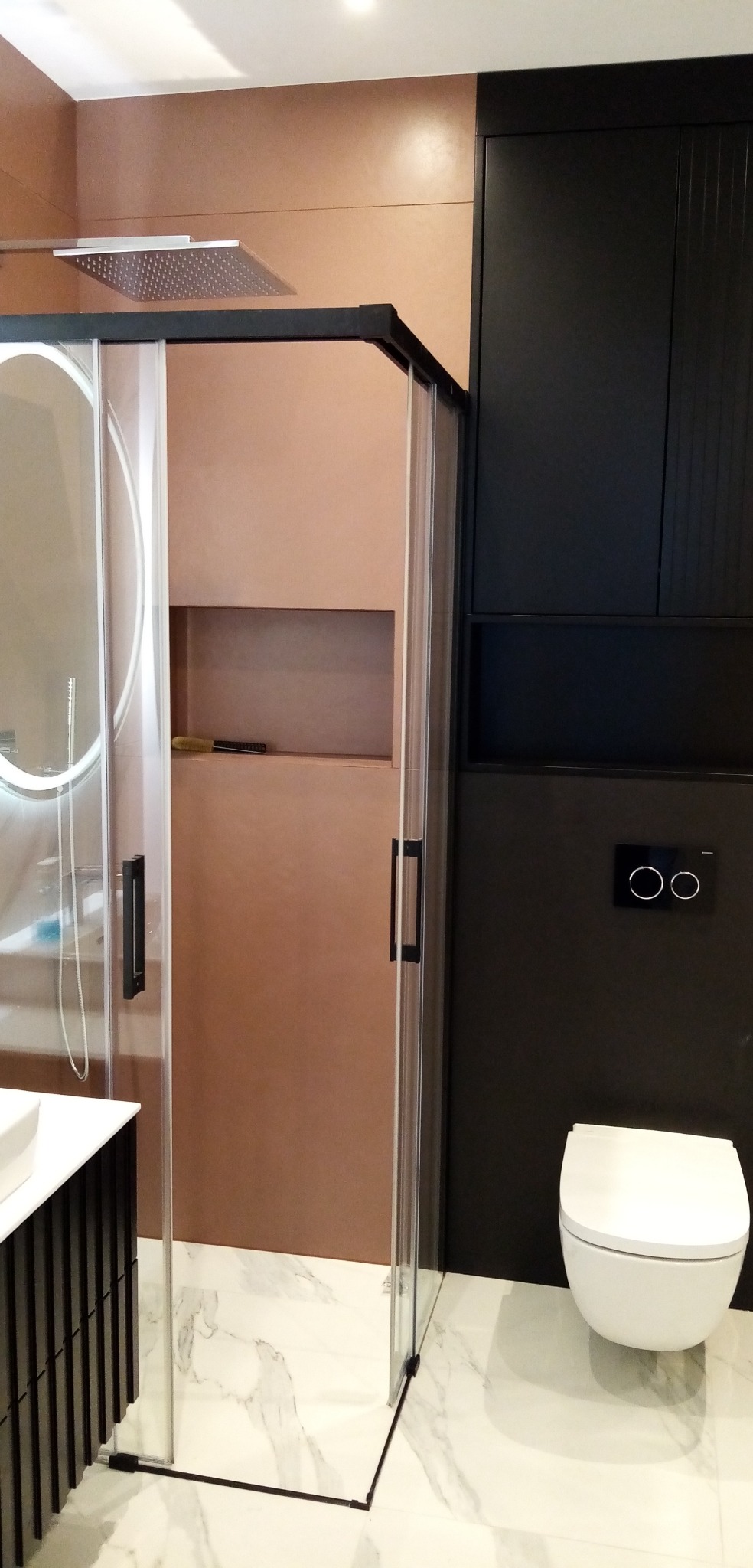 Nowoczesna łazienka z kabiną prysznicową typu walk-in, wykończona w odcieniach brązu i czerni, z marmurową podłogą i minimalistyczną armaturą.