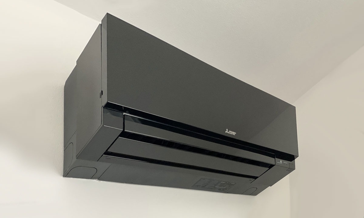 Elegancki, czarny klimatyzator Mitsubishi Electric zamontowany na białej ścianie, widok z dołu, podkreślający nowoczesny design i gładką powierzchnię urządzenia.