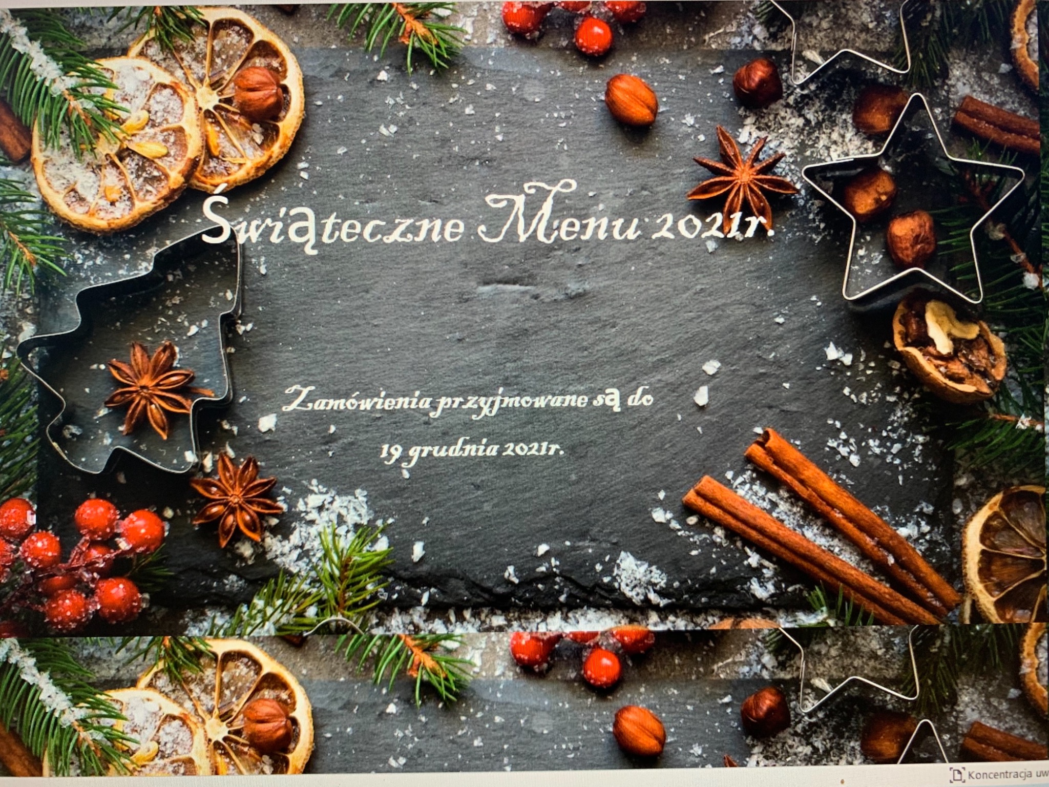 Świąteczne menu 2021 na ciemnym tle z dekoracjami: suszone pomarańcze z orzechami, anyż gwiazdkowy, laski cynamonu, czerwone jagody, gałązki świerku, foremki do ciastek w kształcie choinki...