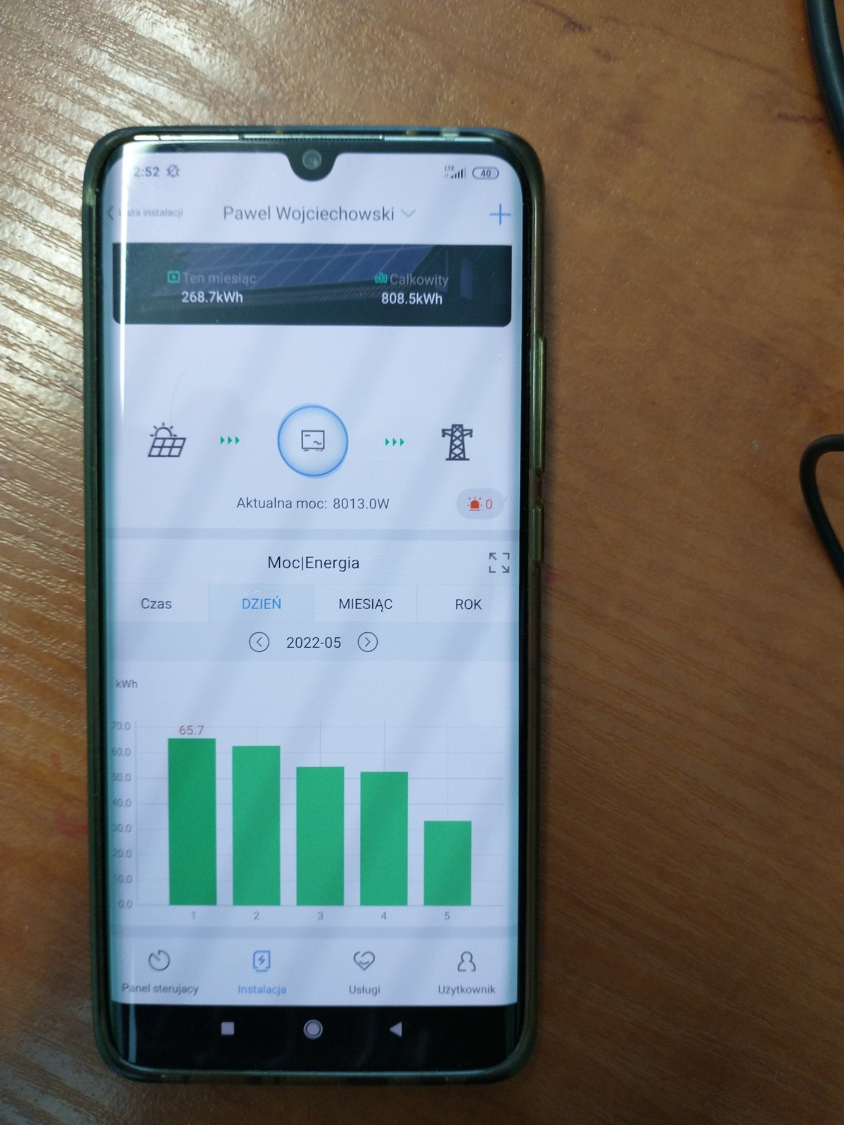 Ekran smartfona prezentujący wykres zużycia energii z paneli słonecznych w maju 2022, z podsumowaniem miesięcznym i całkowitym, w aplikacji monitorującej instalację.