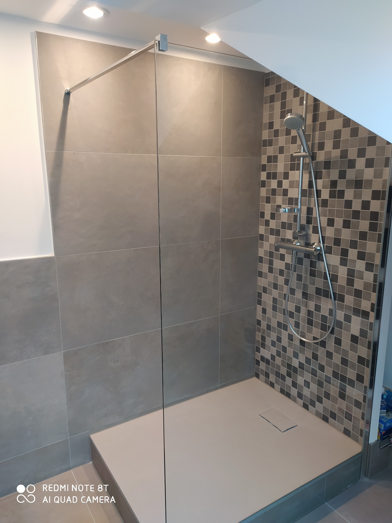 Kabina prysznicowa walk-in z szarą płytką wielkoformatową na ścianach, mozaiką w strefie natrysku i odpływem liniowym w posadzce.