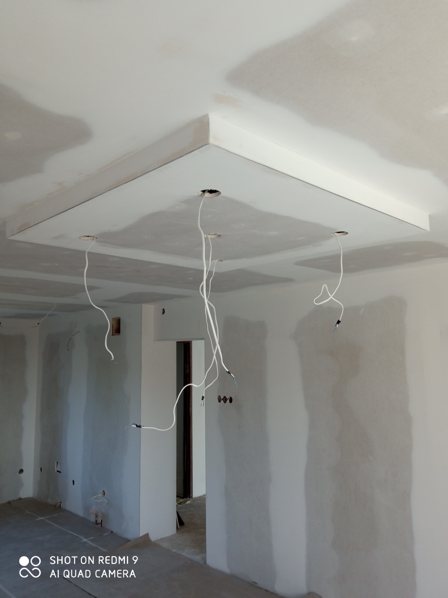 Montaż podwieszanego sufitu z płyt kartonowo-gipsowych w Chełmie, widoczne wystające przewody elektryczne i szpachlowane łączenia płyt na ścianach.