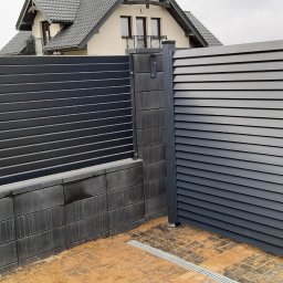Stylbram - Nowoczesne, poziome, szare ogrodzenie z bramką na posesji w Siedliszczach, wykończone elementami z szarego betonu.